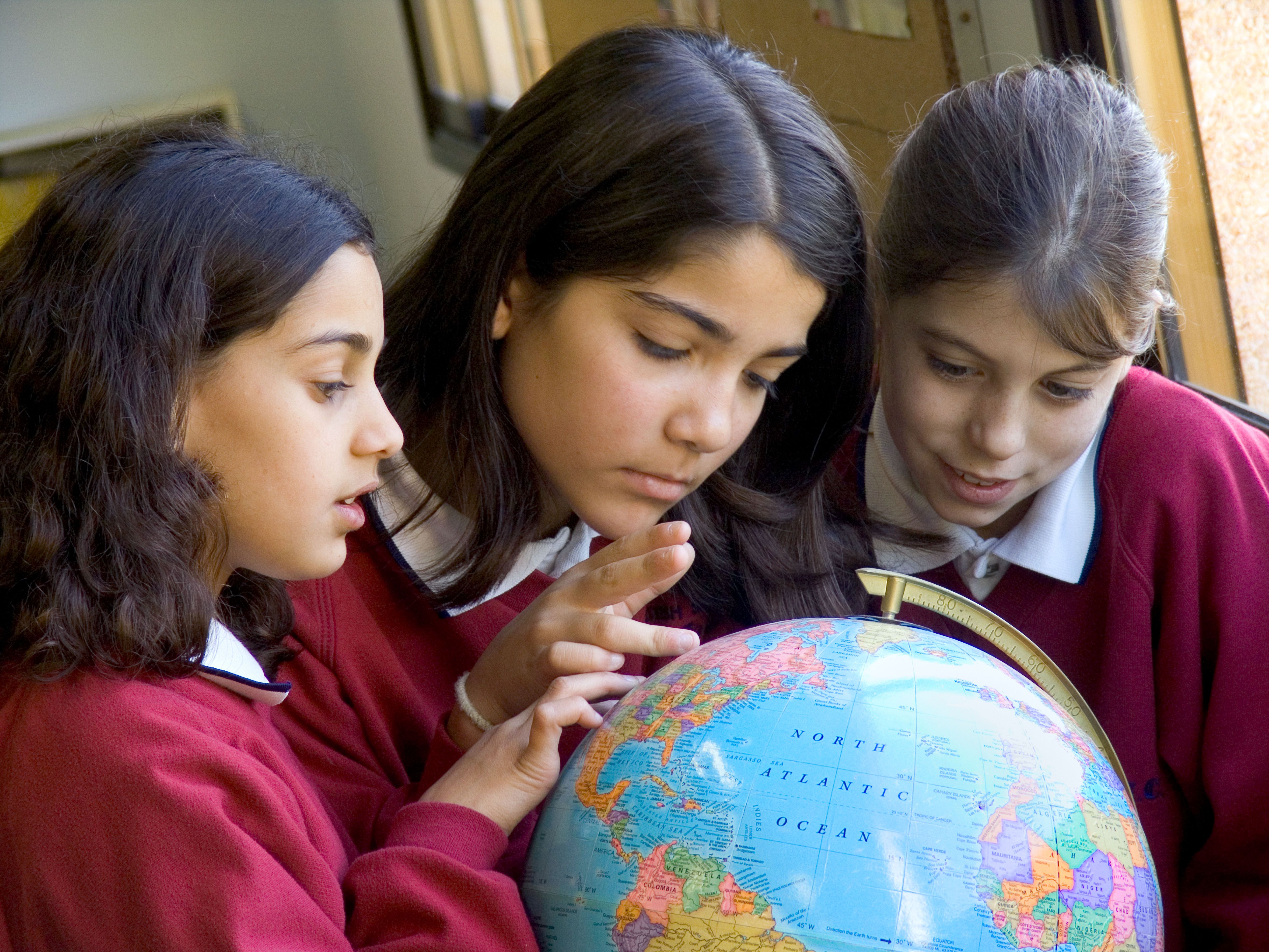 Three school girls studying globe