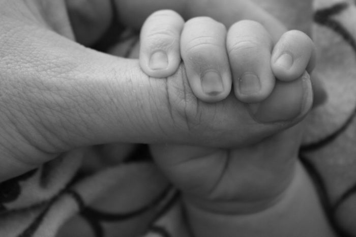 Photo of baby's hand grasping an adult's figure